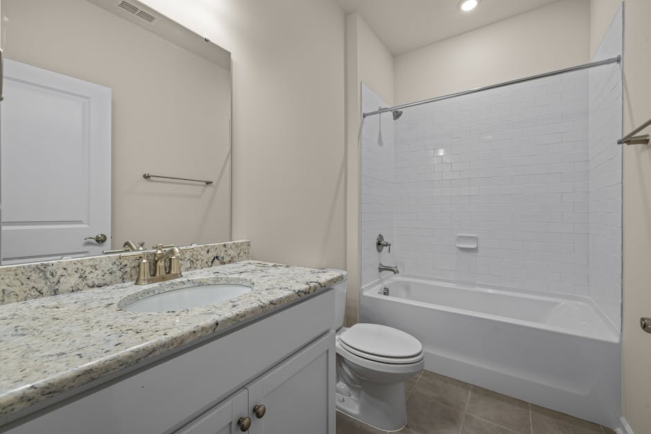 Clean and modern bathroom design featuring granite countertop and a bathtub with white tiles.